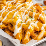 Hero shot of Louisiana voodoo fries with cheese sauce and ranch drizzle